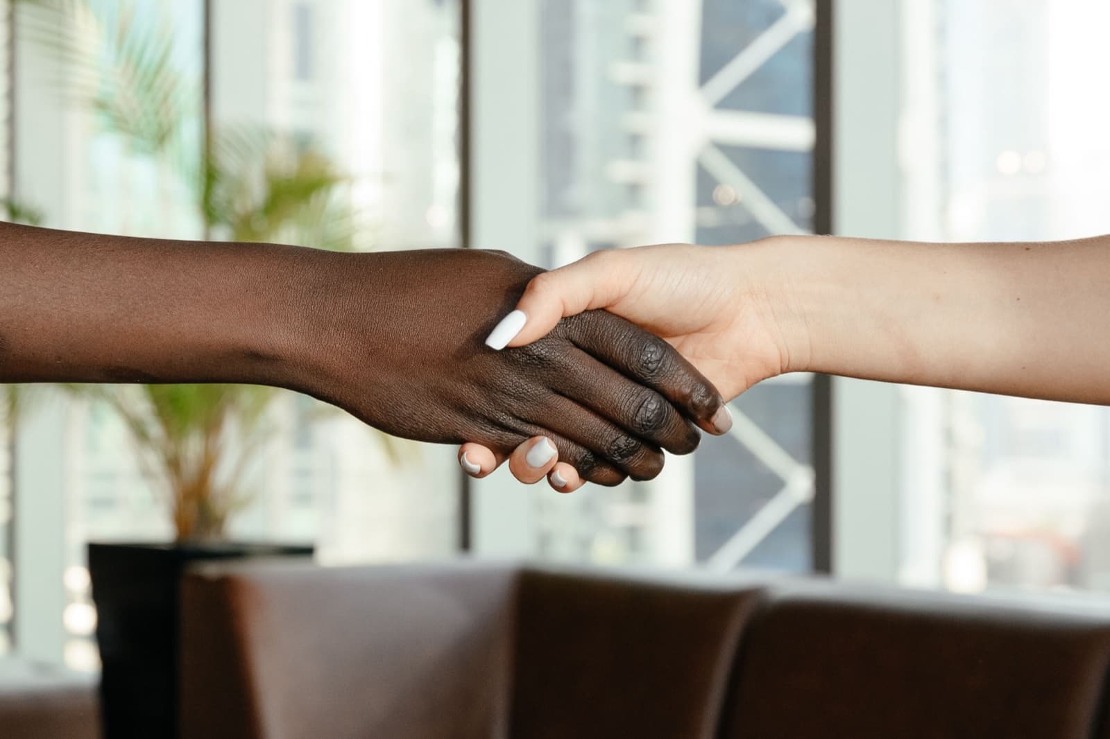 Two people shaking hands across a desk in an office